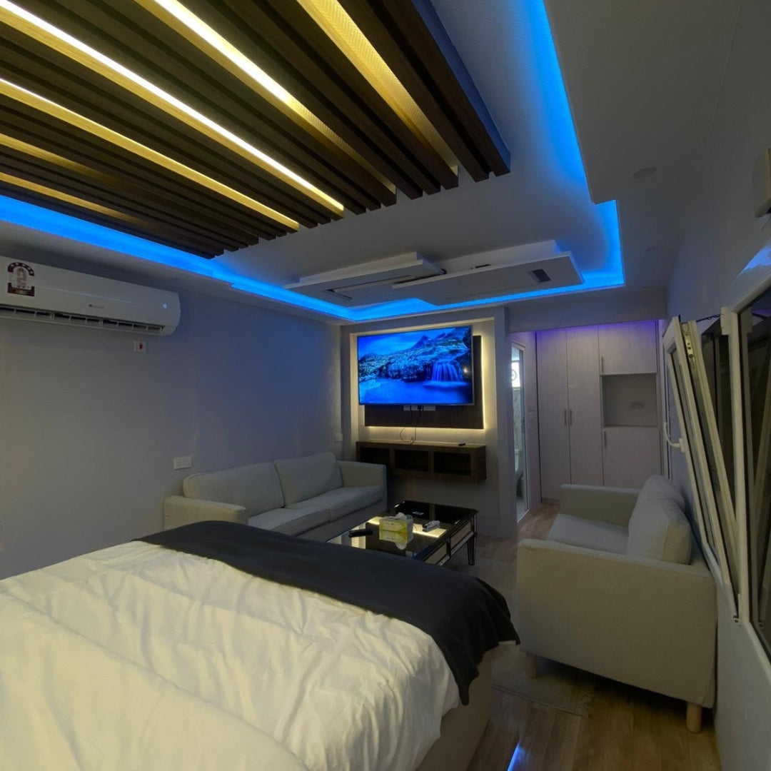 Interior view of the Al Marona VVIP Caravan featuring a large bed, sofa, and modern amenities for a cozy overnight stay.