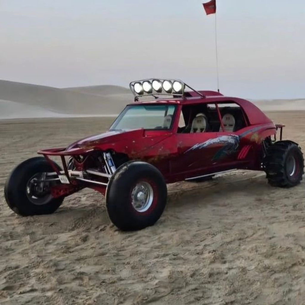 Side view of a powerful buggy bike cutting through sand trails under the clear blue sky.