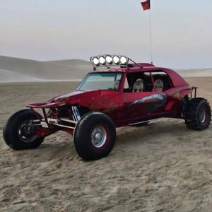 Side view of a powerful buggy bike cutting through sand trails under the clear blue sky.